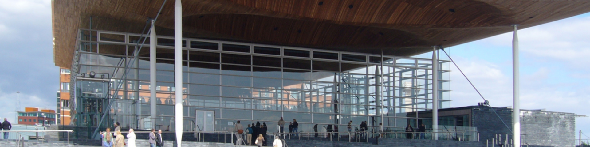 People walk up the steps to the Senedd on a clear blue day.