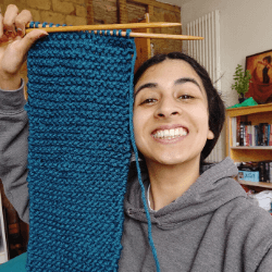 Person smiling and holing a knitted rectangle